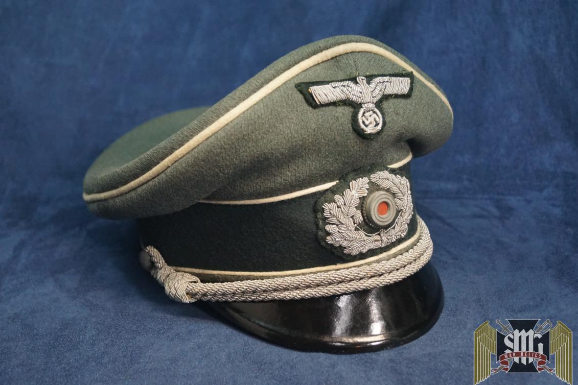 The visor is in great structural condition with no major damage or bill separation. The embroidered eagle and wreath are oxidation free and show some light wear. There are few areas with moth tracking but no holes that go straight through. The white piping is great as well with only a few hard to notice moth spots. The inside is very nice with no issues. The sweat band is in great shape with no rips. Behind it, the cork pad is in good shape. A nice nearly mint example!