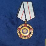 I Class, Gold wreath, Red enamel Star, words in Gold on Yellow background disc, Gold center motif, II Class, Silver wreath, Red enamel Star, words in Silver on Yellow background, Silver center motif, III Class, Bronze wreath, Red enamel Star, words in bronze on yellow background, Silver center motif.